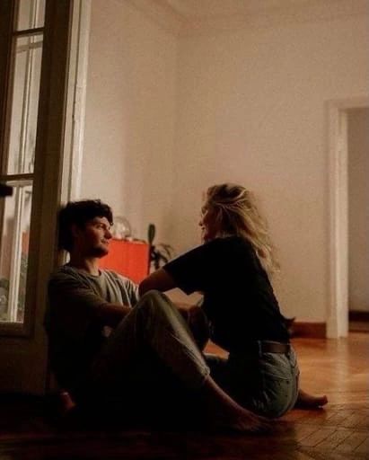 a man and woman sitting on the floor in front of a door looking at each other