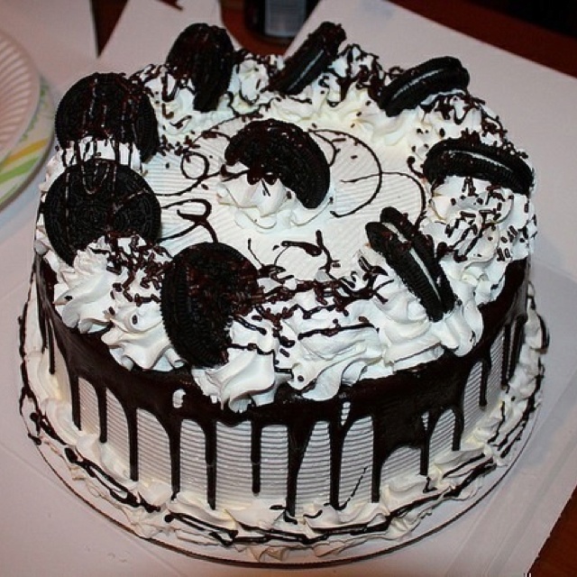 a cake with white frosting and oreo cookies on top sitting on a table