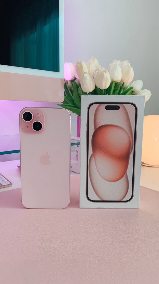 two iphones sitting next to each other on a table with flowers in the background