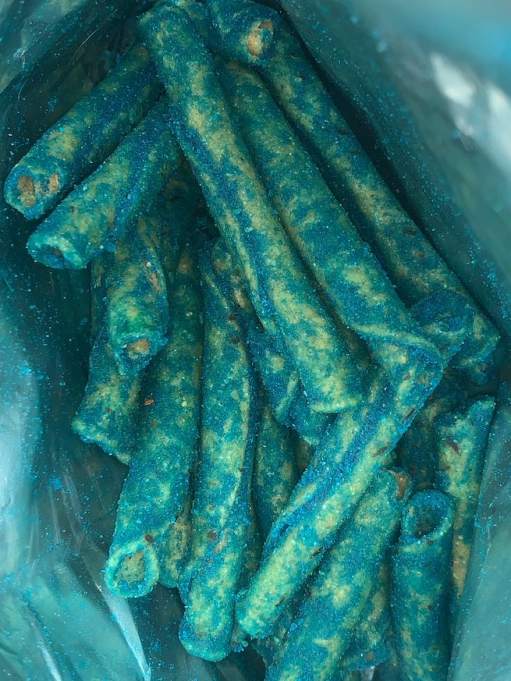 there is a bag full of green candy sticks in the blue plastic wrapper on the table