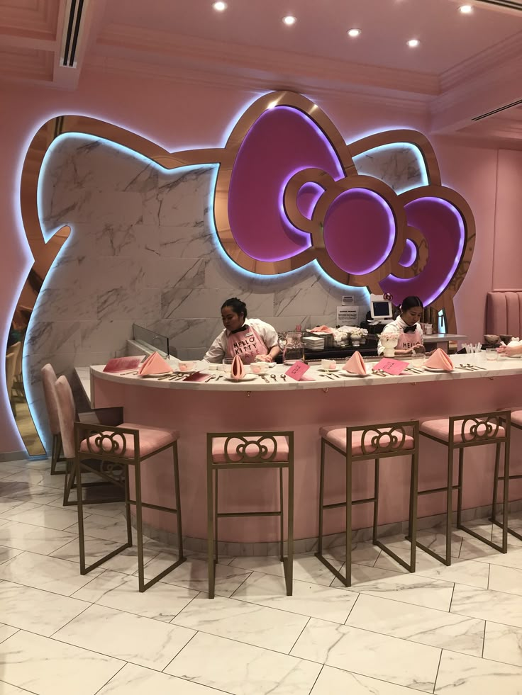 a dining room with a hello kitty sign on the wall and pink chairs around it