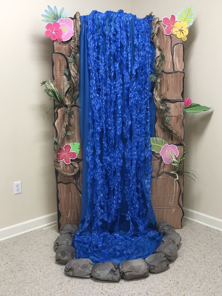 a blue curtain with flowers on it in front of a stone wall and rock garden