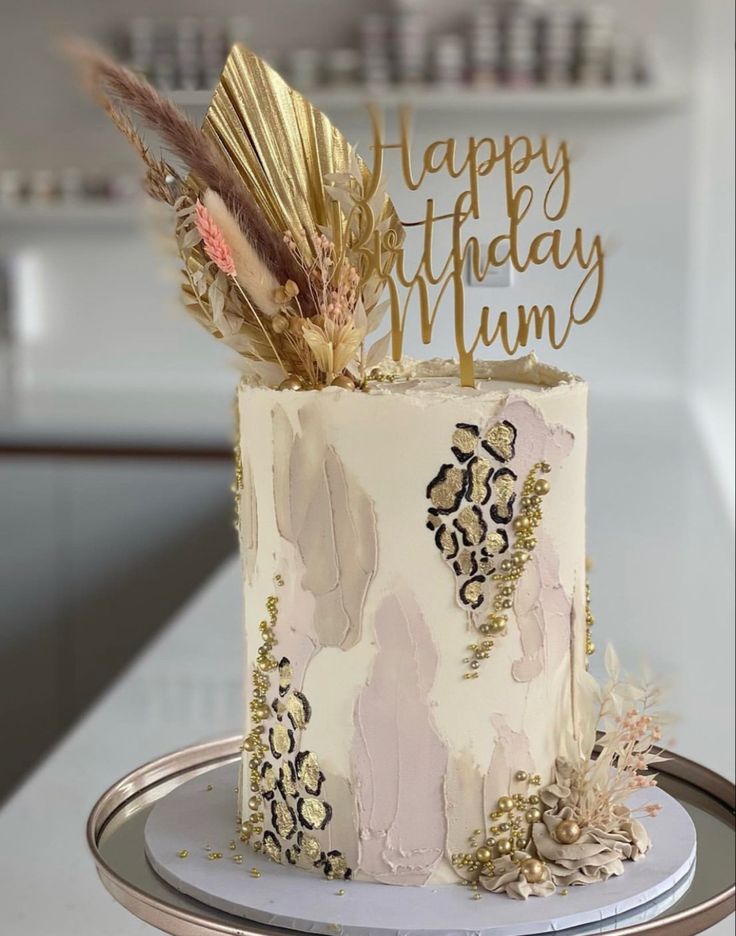 a white and gold birthday cake with feathers on top