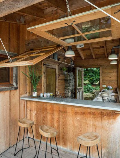 an outdoor bar with three stools in front of it and wood paneling on the walls