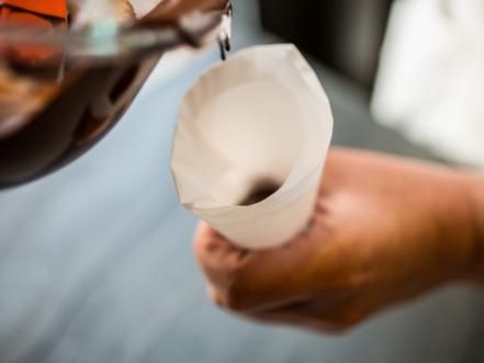 someone is pouring something out of a paper cup to another person who is holding it