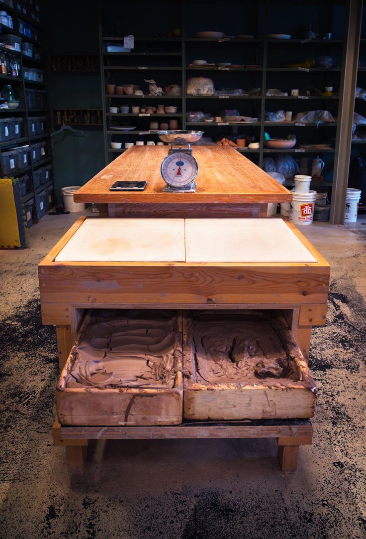 a wooden table with two drawers and a scale on it in a room full of shelves