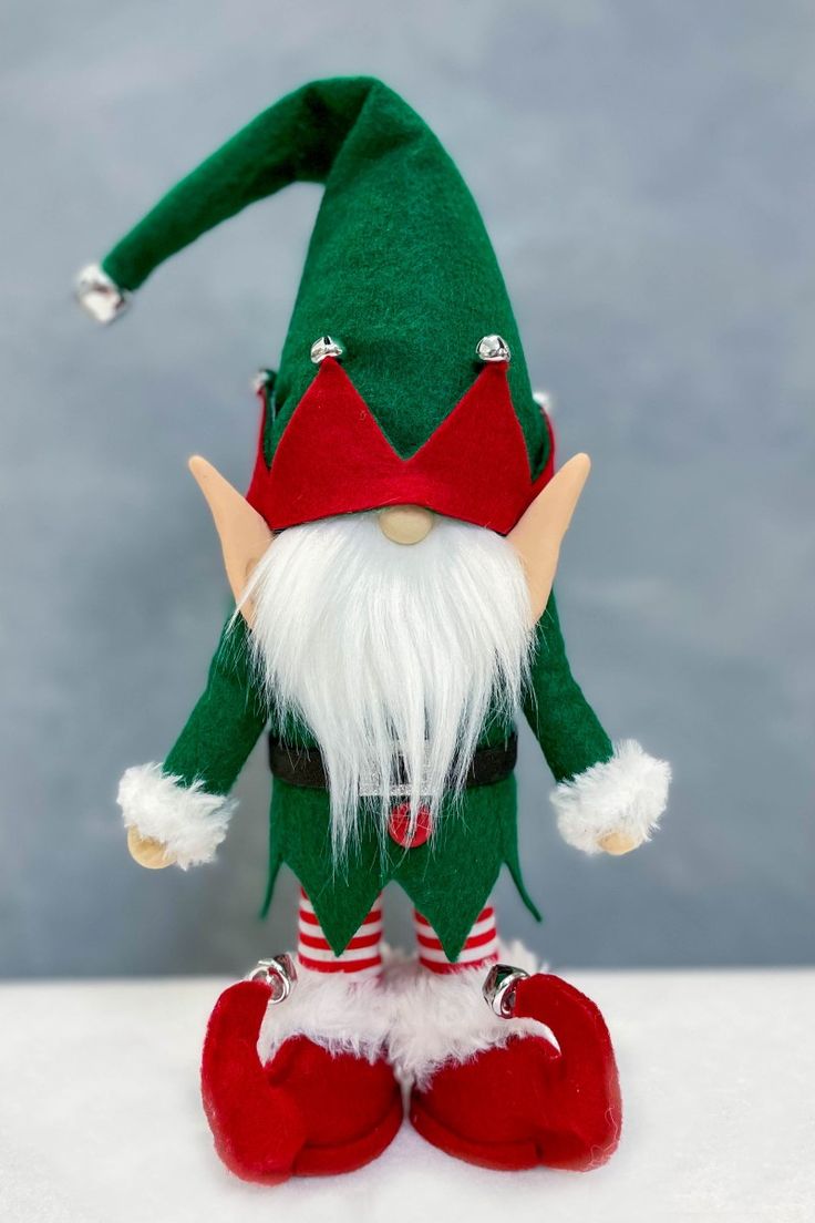 a green and red elf doll sitting on top of a white table