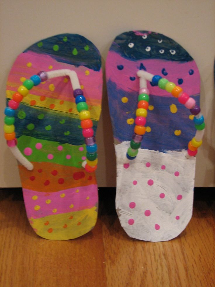 two colorful flip flops with beads on them sitting next to each other in front of a wall