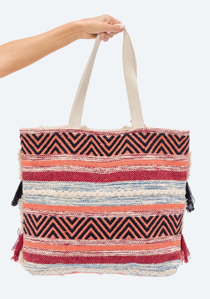 Fringed, zig-zag tote bag with hanging tassel detail. Featuring a striped, multi-patterned design on the back of the tote - this is the perfect bohemian summer bag for beach days and weekend trips! Zig zag pattern Fringe detail Removable hanging tassel Self: 60% Cotton, 40% Acrylic, Lining: 100% Polyester Dimensions: 19" x 15"Style: DR-4476-1 Striped Woven Tote Bag, Bohemian Multicolor Beach Bag With Tassels, Red Beach Bag With Tassels, Bohemian Tote Beach Bag With Tassels, Bohemian Tassel Tote Beach Bag, Red Bohemian Beach Bag For Shopping, Red Bohemian Shoulder Bag With Braided Handles, Multicolor Tote Bag With Tassels, Multicolor Tassel Tote Bag