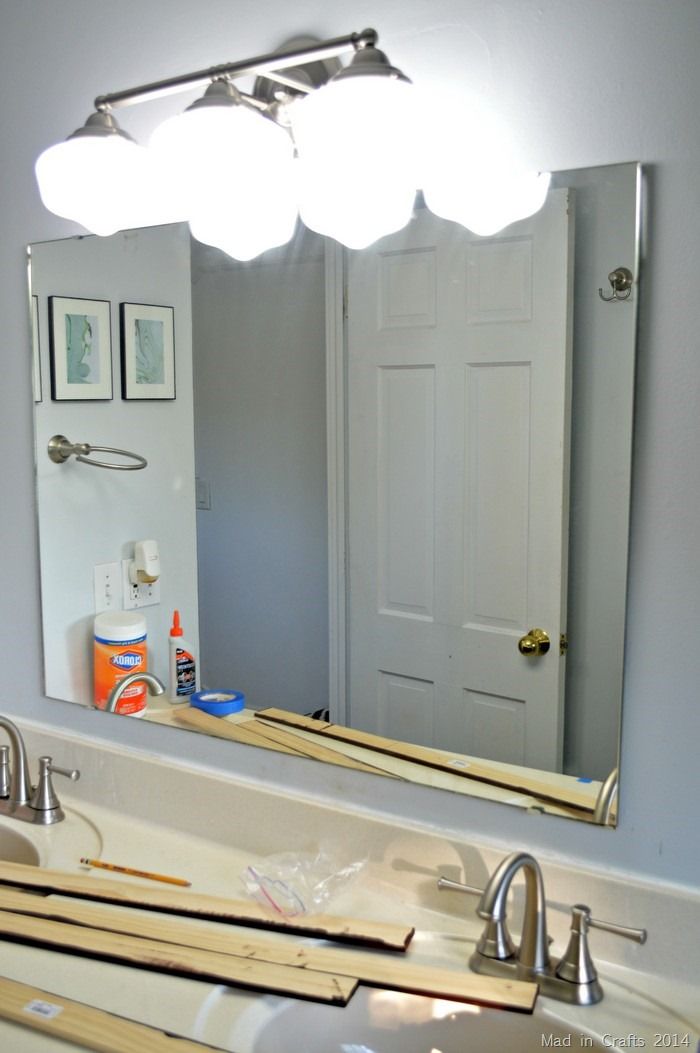 a bathroom sink under a large mirror next to a door and light fixture on the wall