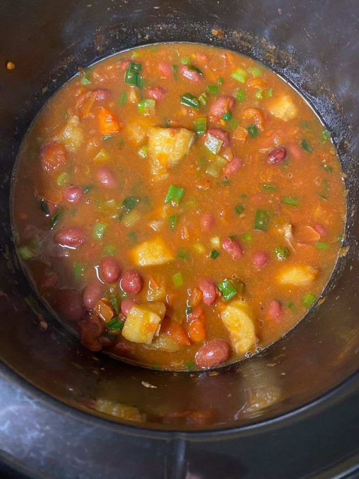 a pot filled with stew and vegetables on top of a stove burner in the process of being cooked