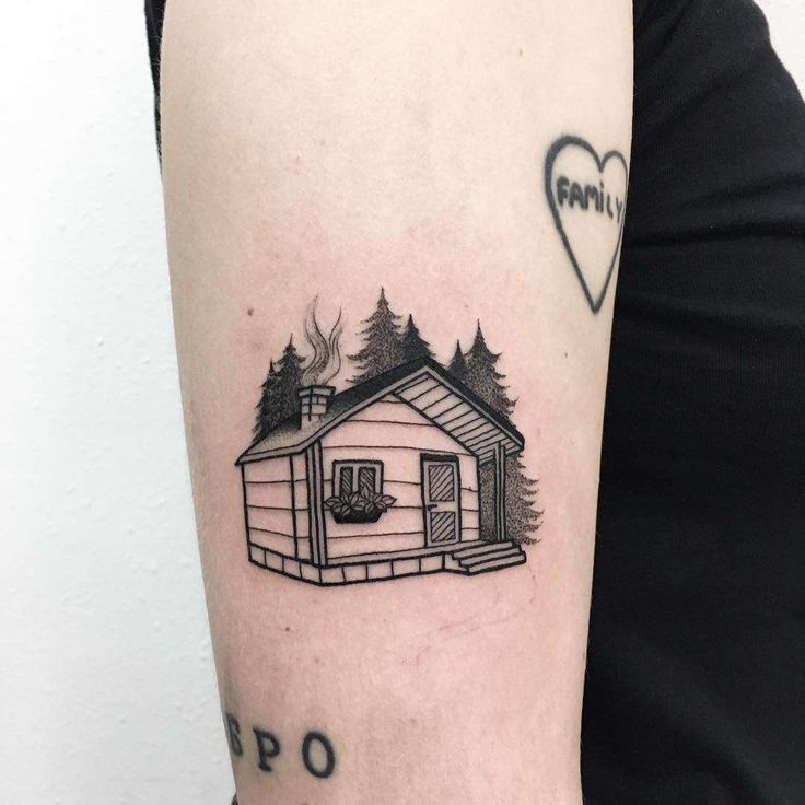 a woman's arm with a small house tattoo on it