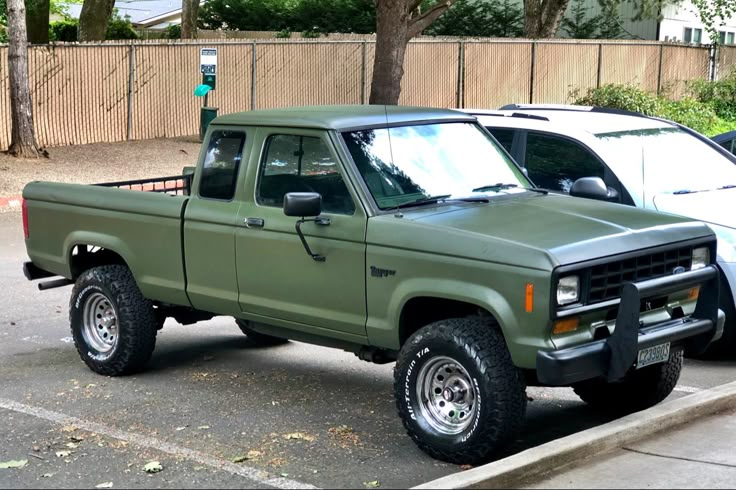 a green pick up truck parked in a parking lot