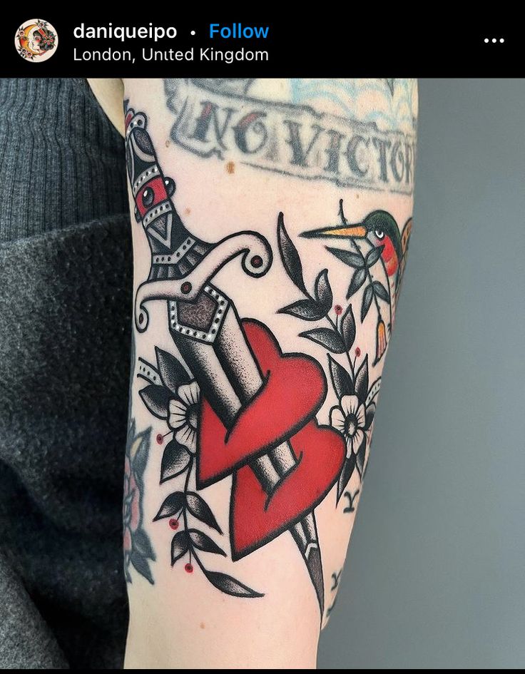 a woman with a tattoo on her arm holding a red heart and two black birds