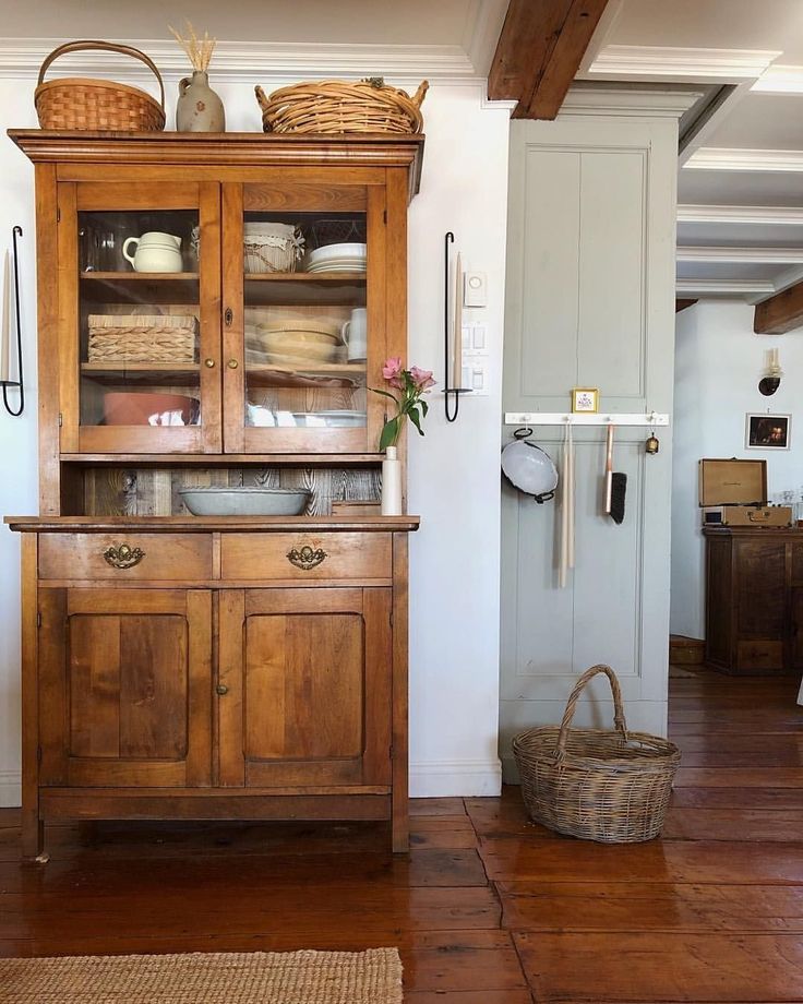 an old wooden hutch with baskets on top in a living room next to a door