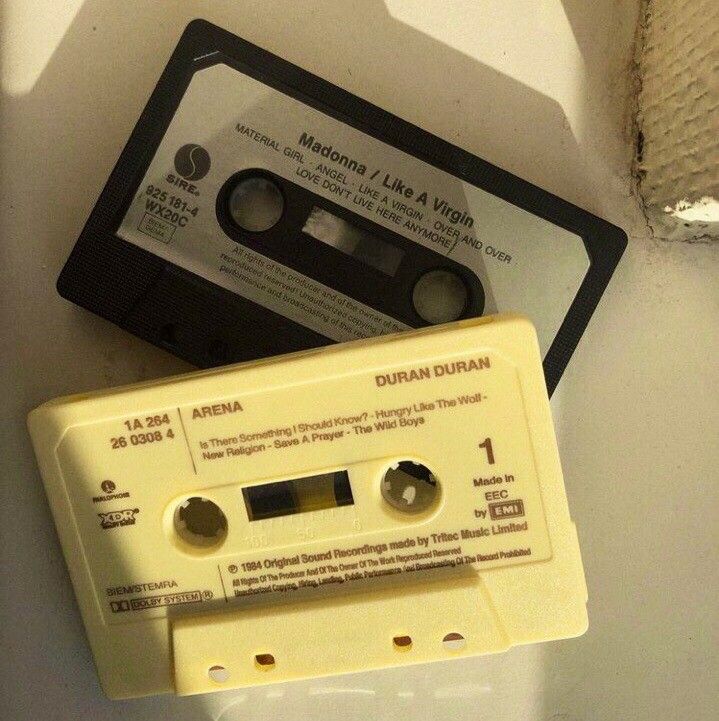 an old yellow and black tape recorder sitting on top of a white wall next to a cassette player