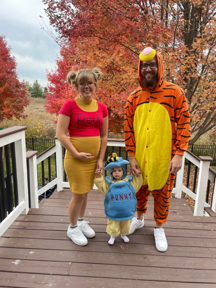 a man and woman in winnie the pooh costumes standing on a porch with a child