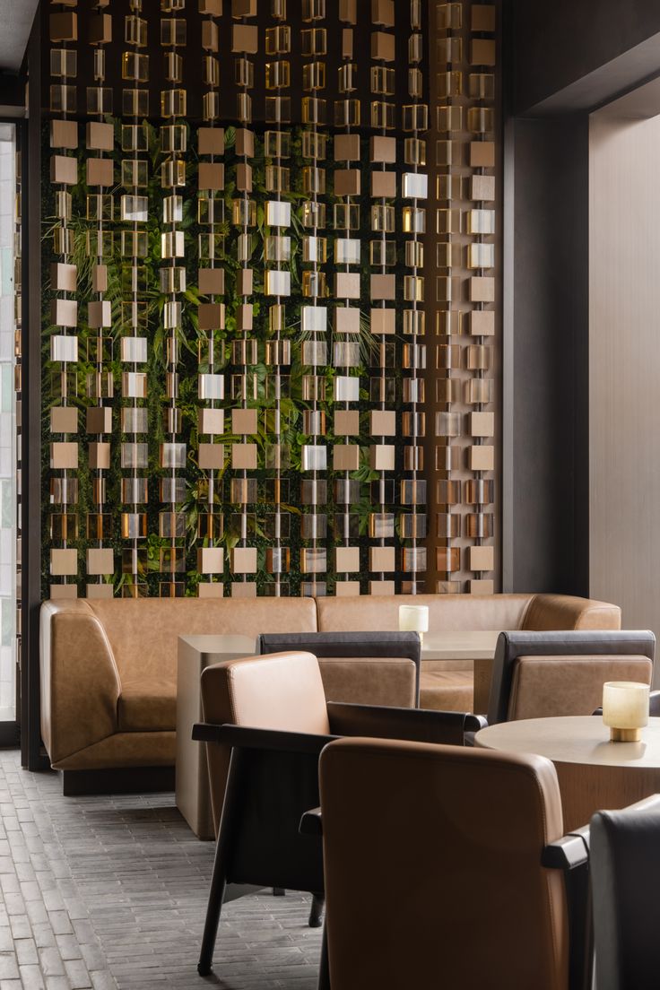 the interior of a restaurant with tables, chairs and plants on the wall behind them