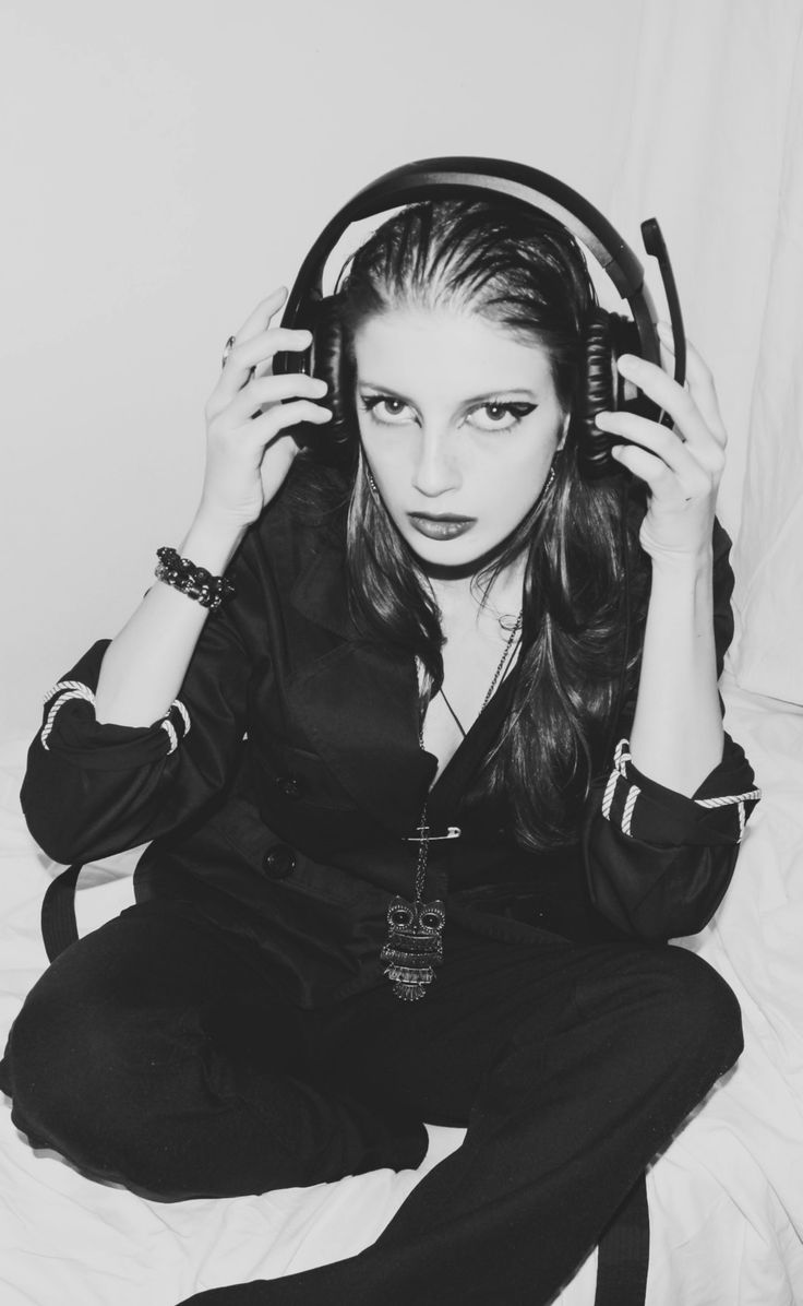 a woman sitting on top of a bed holding headphones