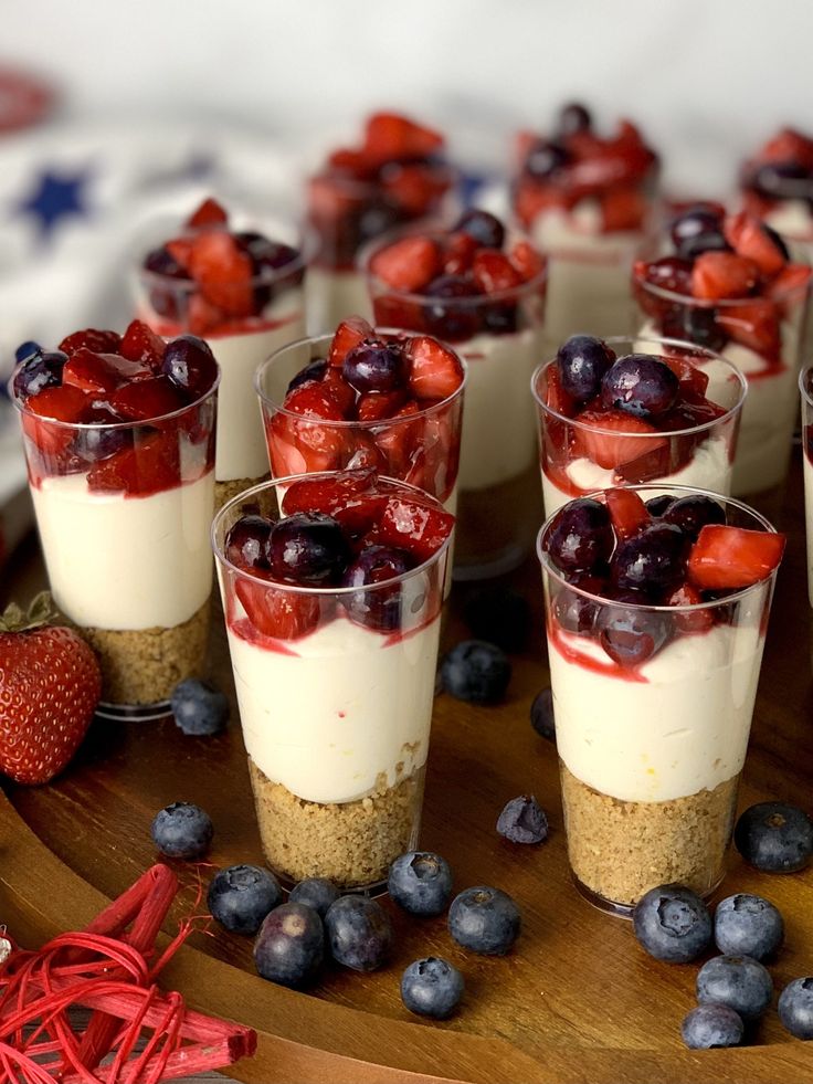 small desserts are arranged on a wooden platter with berries and blueberries in them