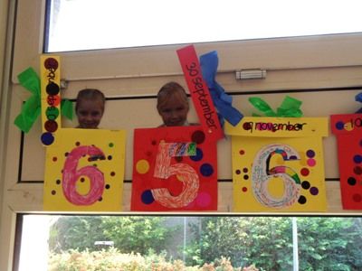 two children are sitting in front of a number sign made out of construction paper and cardboard