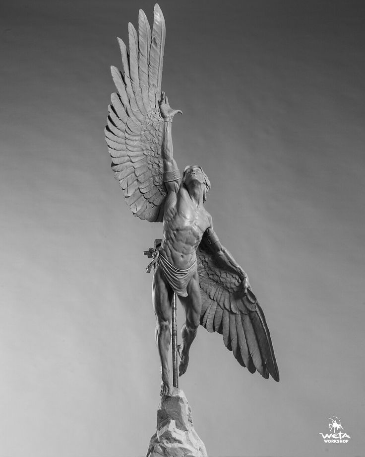 a black and white photo of a statue of a man with wings on top of a rock