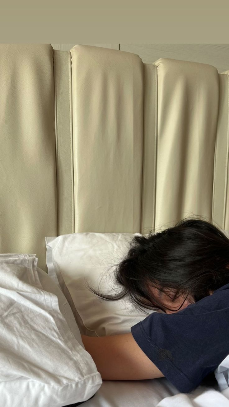 a woman laying in bed with her head on the pillow