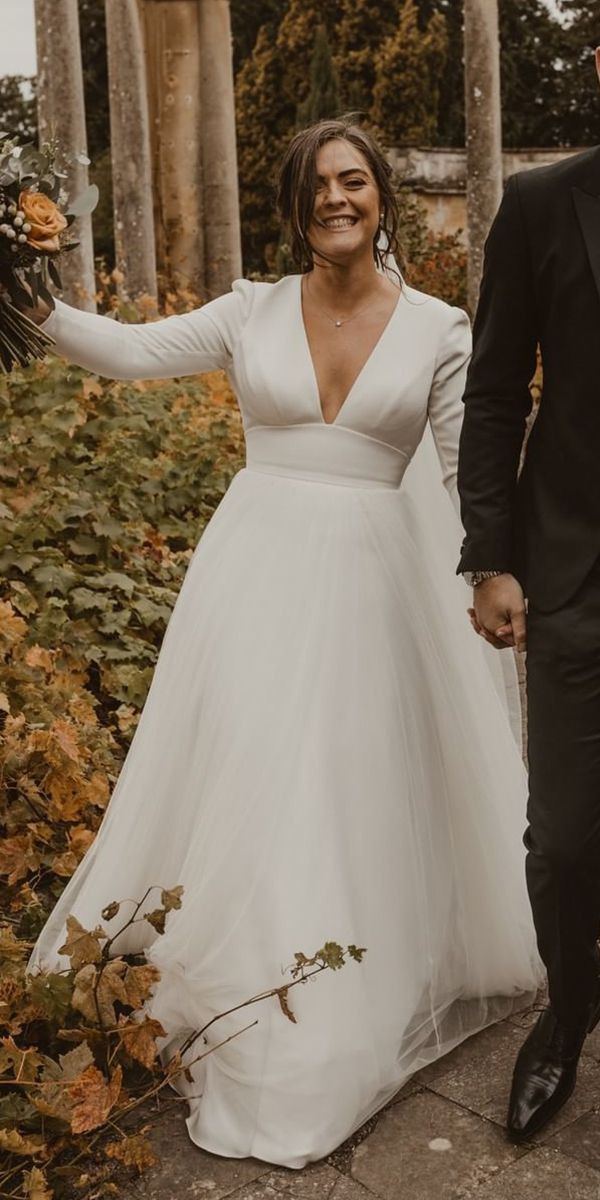 a bride and groom are walking through the park holding each other's hands as they smile