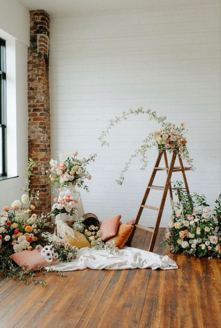 an arrangement of flowers and greenery on the floor in front of a brick wall