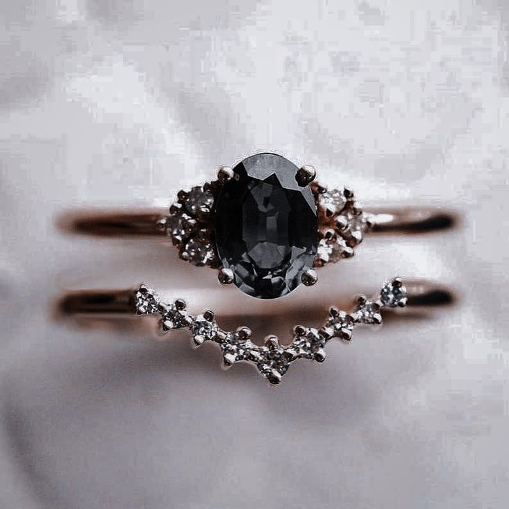 two wedding rings with an oval cut black diamond