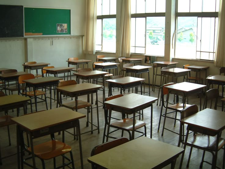 an empty classroom with desks and chalkboard on the wall in black and white