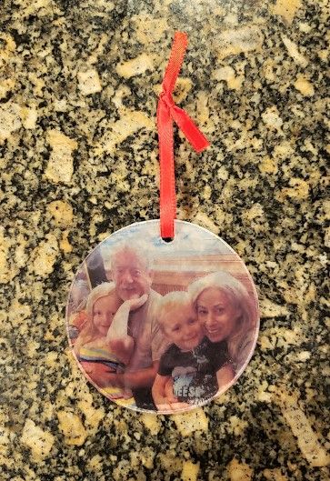 an ornament hanging on a granite counter top with a red ribbon around it