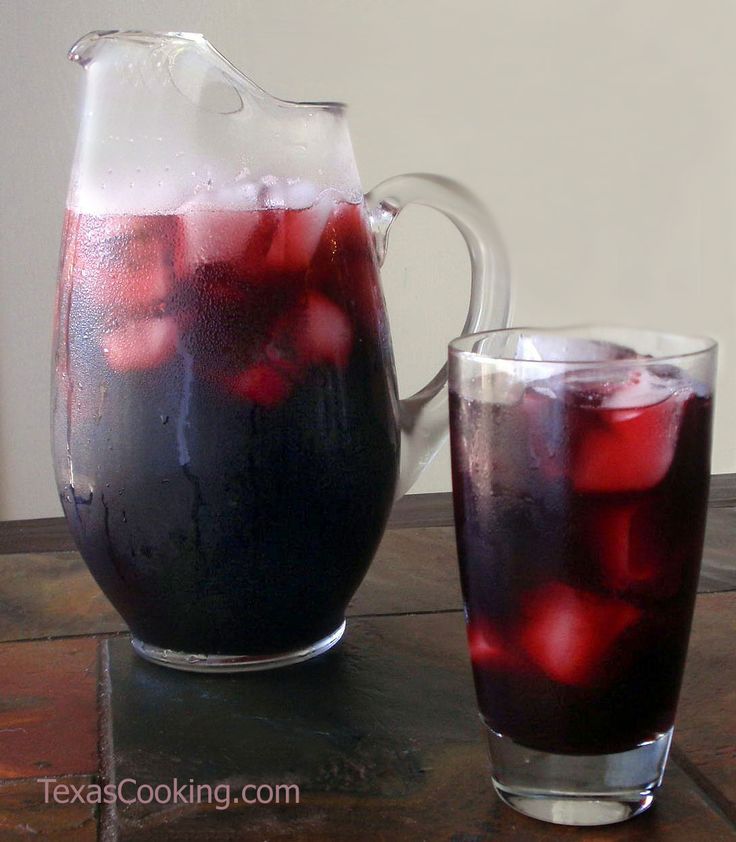 two pitchers filled with liquid sitting next to each other on top of a wooden table