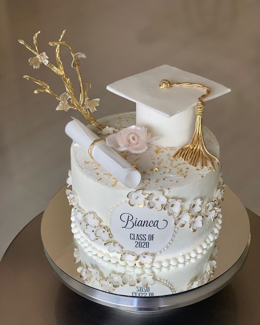 a white cake with gold decorations and a graduation cap on top