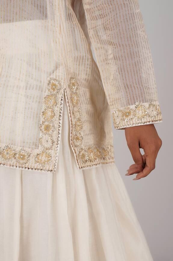 White chanderi lehenga with an attached cancan and gota embroidery. Comes with a dabka work padded blouse, a choli and a tissue and organza dupatta.
Components: 4
Pattern: Embroidered
Type Of Work: Gota, Dabka
Neckline: Blouse : V Neck, Choli : U Neck
Sleeve Type: Blouse : Sleeveless, Choli : Full
Fabric: Chanderi, Dupatta : Tissue and Organza
Color: White
Other Details: 
Lehenga Length : 43 inches
Model Height : 5 ft 5 inches, wearing size S
Closure : Blouse - Back hooks
Occasion: Wedding - Aza Chanderi Lehenga, Gota Embroidery, Dabka Work, Chanderi Dupatta, Padded Blouse, Types Of Work, Blouse Sleeveless, Organza Dupatta, U Neck