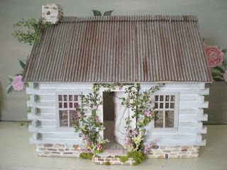 a doll house made out of clay with flowers on the outside and windows in the front