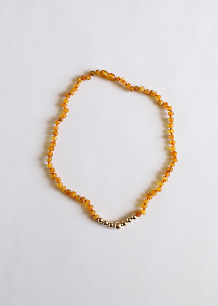 a yellow beaded bracelet with silver beads on a white background, showing the clasp