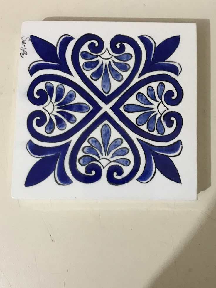 a blue and white tile with an intricate design on the bottom, against a white background