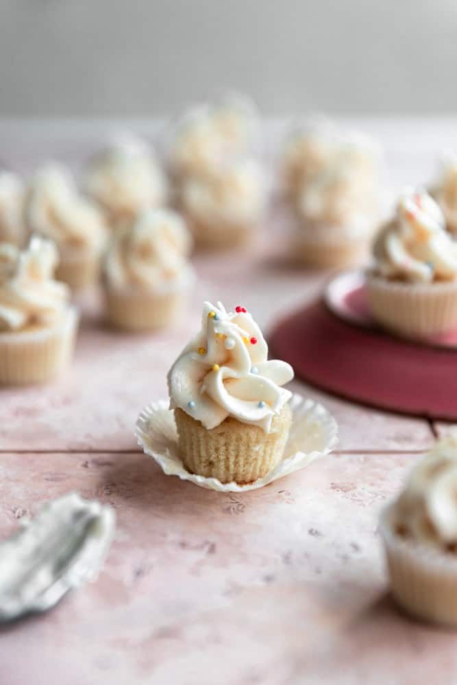 small cupcakes with white frosting sitting on a table