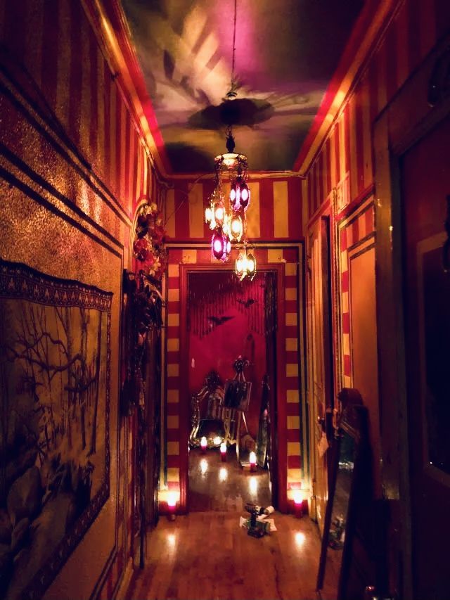 the hallway is decorated with red and yellow striped walls, chandeliers, and candles