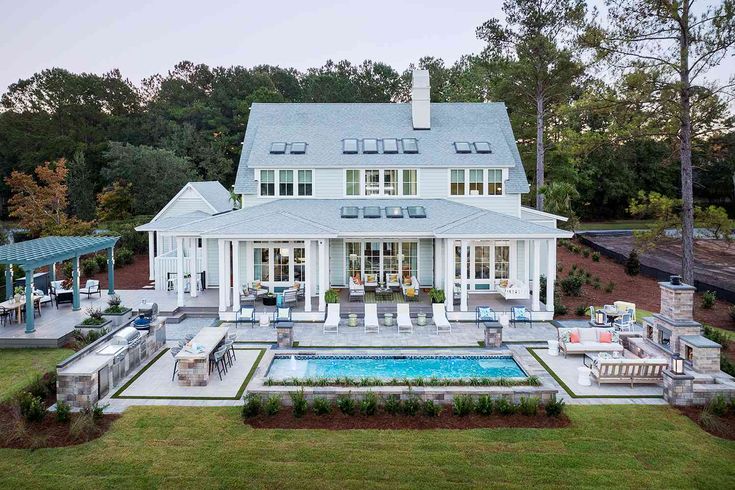 an aerial view of a house with a pool in the foreground and covered patio