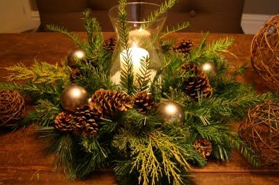 a candle is lit on a table with pine cones and evergreen branches