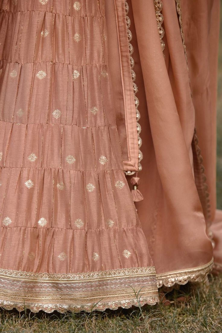 Editor's Note Featuring a zardozi embroidered brocade based blouse with brocade multi tiered lehenga with belt and embroidered organza dupatta Color: Neutral pink Fabric: Brocade Sleeve: Half Neckline: Sweetheart Embroidery details: Zardozi Component: Blouse, Lehenga, belt and dupatta Lehenga length: 43" inches and blouse: 14" inches Occasion: Haldi, mehndi, sangeet and bridesmaid Care: Dry clean only About the Designer Shyam Narayan Prasad started his journey in the Indian Fashion Design Indust Pink Raw Silk Palazzo Set For Reception, Designer Tiered Skirt Sharara With Dupatta, Designer Traditional Tiered Lehenga, Fitted Set With Dupatta And Tiered Skirt, Anarkali Wedding Sharara With Tiered Skirt, Anarkali Sharara With Tiered Skirt For Wedding, Georgette Sharara With Tiered Skirt For Receptions, Diwali Sharara With Zari Work And Tiered Skirt, Bollywood Style Tiered Skirt Sharara For Reception