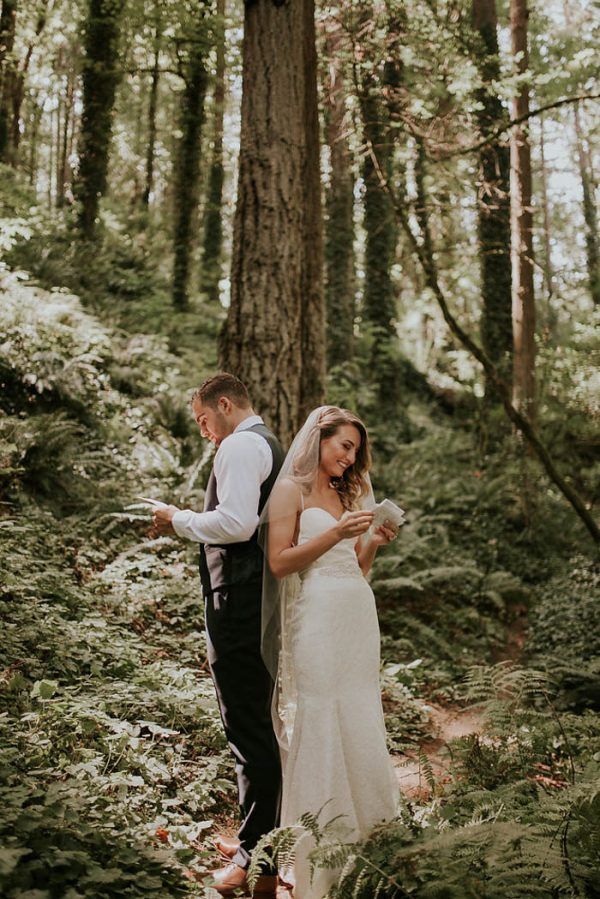 a bride and groom standing in the woods