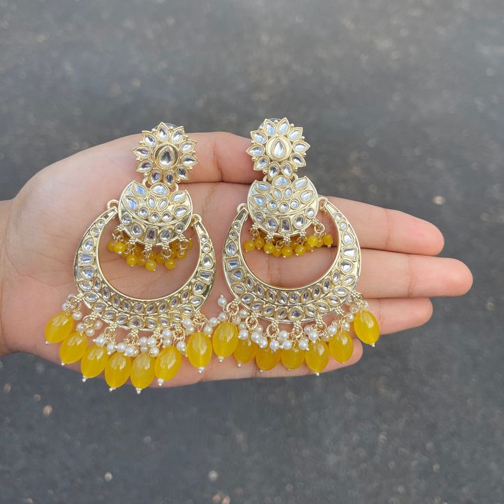 The Yellow Sayana Earrings are lightweight chandbalis with Kundan and Gold-Plating on beautiful beaded crystals. Specifications Materials used: Kundan, beaded crystals, Gold Plating Weight: 24 g Height: 3 inches At Romikas, we pride ourselves on the craftsmanship and high quality of our jewelry, designed to enhance your natural beauty. Please contact us with any questions. Traditional Beaded Chandbali Danglers, Beaded Chandbali Danglers For Festivals, Chandbali Beaded Danglers For Festivals, Bollywood Style Chandbalis With Dangling Beads For Diwali, Bollywood Chandbalis With Dangling Beads For Diwali, Gold Chandbali Chandelier Earrings With Dangling Beads, Jeweled Chandbali Chandelier Earrings For Celebration, Festival Chandbali Earrings With Dangling Beads, Festive Beaded Chandbali Chandelier Earrings