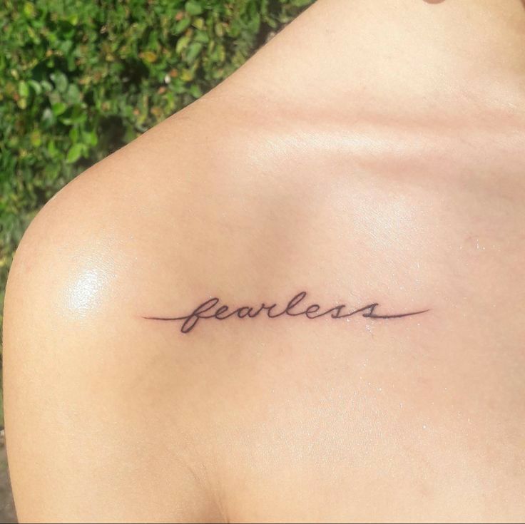 the back of a woman's shoulder that says fearless in cursive writing