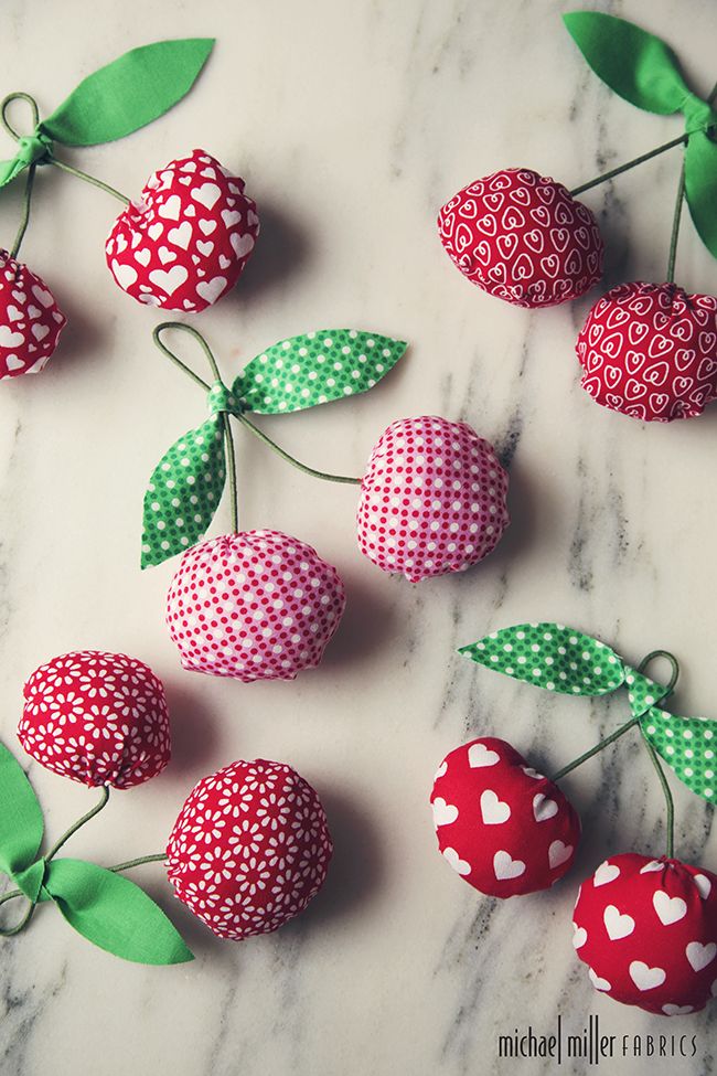 some fabric covered strawberries are sitting on a marble surface with green leaves and hearts