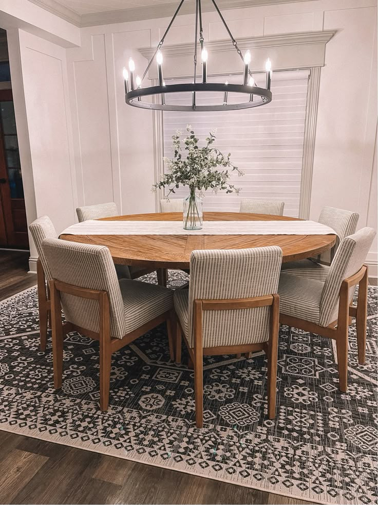 a dining room table with six chairs and a chandelier hanging from the ceiling