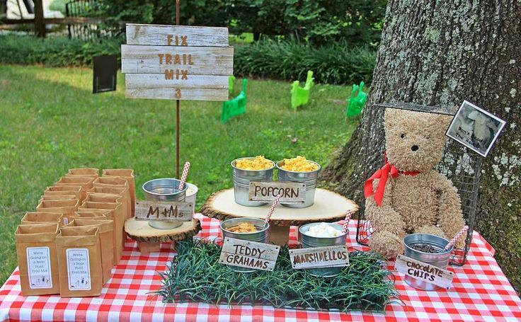 a teddy bear sitting on top of a table next to a picnic sign and food