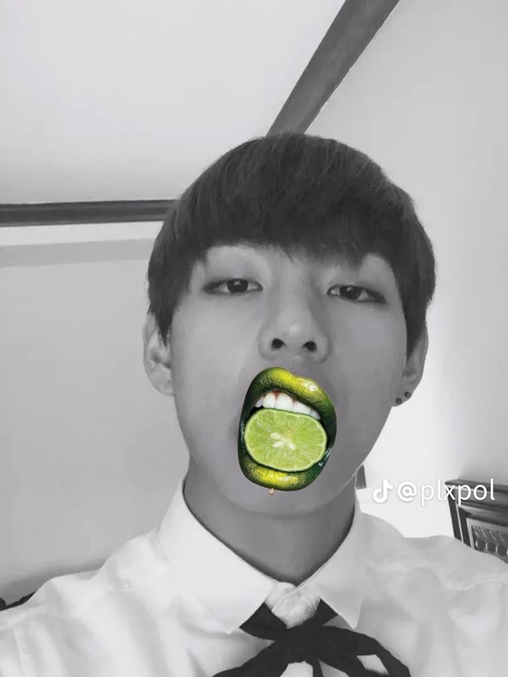 a young man wearing a tie and holding a slice of lime in his mouth with the word pickle on it